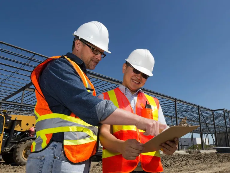 Deux ingénieurs en équipement de sécurité examinent un document sur un chantier industriel